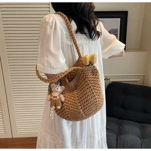 Close-up detail of a handmade woven shoulder bag with a cute bear plush pendant attached