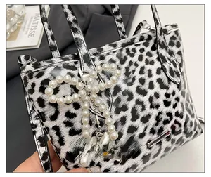 Detail of leopard print crossbody bag with pearl bow charm and silver heart pendant