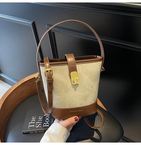 Detail of vintage canvas and leather bucket bag with metal clasp and adjustable strap