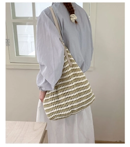Detail of green and white striped woven tote bag with adjustable leather shoulder strap