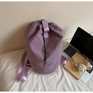 Detail of lavender drawstring bucket backpack with nylon texture on white bedding
