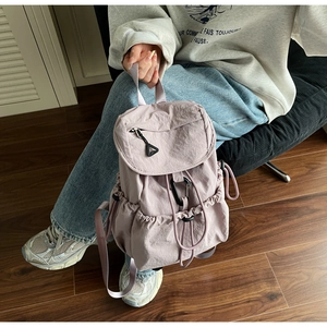 Dettaglio di uno zaino in nylon viola chiaro con coulisse e chiusura a patta pieghettata