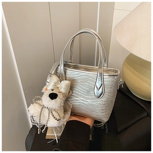Detail of silver sequin tote bag with wave texture and cute plush puppy charm