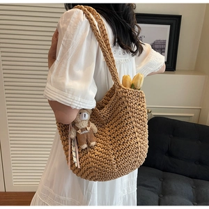 Detail of hand-woven camel shoulder bag with a cute bear charm in a home setting