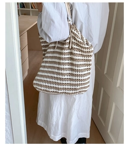 Detail of hand-woven striped straw tote bag with soft texture and chic tassel fringe