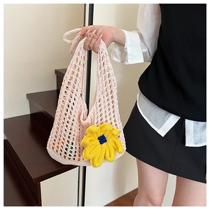 Close-up of pink crochet tote bag featuring a vibrant 3D yellow and blue knit flower detail