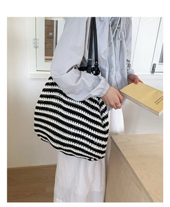 Close-up of black and white striped woven tote bag with adjustable leather shoulder strap