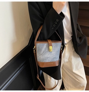Detail of the blue denim bucket bag with brown leather trim and golden metal clasp