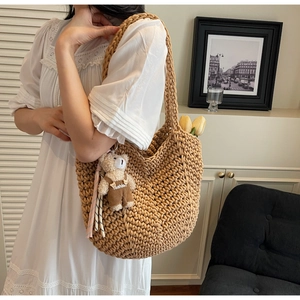 Detail of hand-woven crochet shoulder bag with cute teddy bear charm and tulip decoration