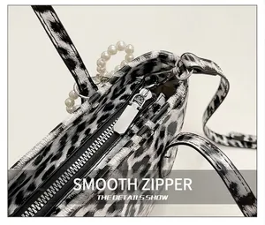 Close-up of leopard print crossbody bag featuring silver zipper and pearl handle detail
