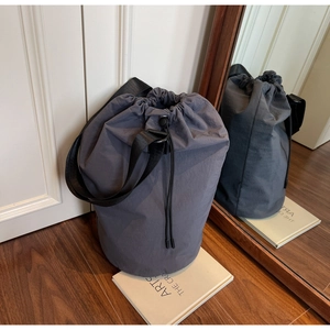 Detail showing the gray nylon drawstring bucket bag with its adjustable wide shoulder strap