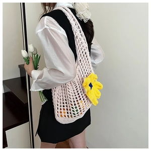 Detail of hand-woven hollow knit tote bag featuring a large yellow daisy flower accent