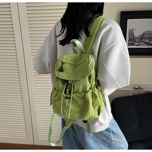 Dettaglio dello zaino in nylon verde erba con chiusura a coulisse e fibbia di regolazione
