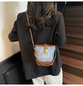 Blue-grey bucket bag with brown leather trim shown on model with gold hardware detail