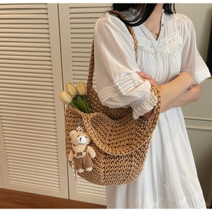 Detail of hand-knitted tote bag featuring tulip decor and a plush bear pendant charm