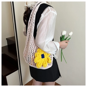 Detail of pink hand-crocheted hollow knit bag with a large yellow sunflower accent