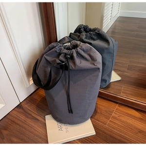 Macro detail of dark grey nylon drawstring bucket bag on a magazine in home setting