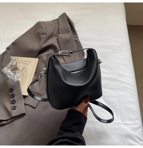 Detailed view of black litchi pattern leather handbag with silver metal hardware