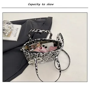 Detail view of the leopard print crossbody bag showing spacious interior with pearl charm