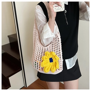 Detailed close-up of a pink woven hollow-out beach bag with a large yellow knit flower charm