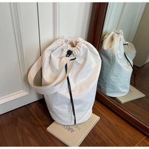 Detailed shot of an off-white canvas drawstring bucket bag resting on an arts book