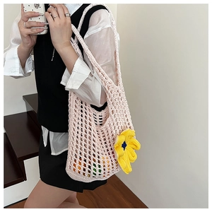 Close-up of pink hollow knit crochet bag with a vibrant yellow floral charm accessory