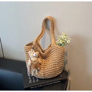 Detail of camel woven bucket bag with cute bear charm and daisy decor on art books