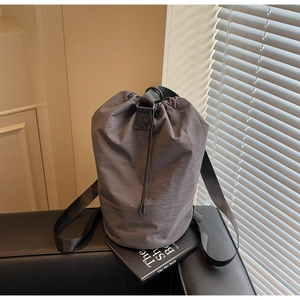 Detail of dark grey drawstring bucket bag with textured nylon fabric and wide strap