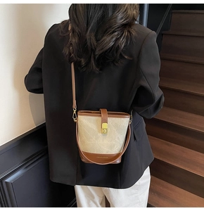 Detail of the chic beige fabric bucket bag with brown leather trim and golden twist lock
