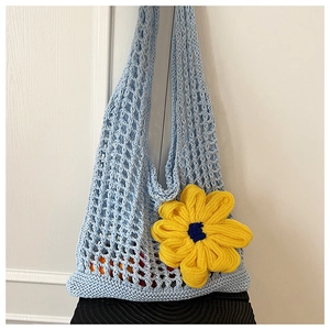Detail of light blue hollow crochet bag featuring a large 3D yellow woven flower accent