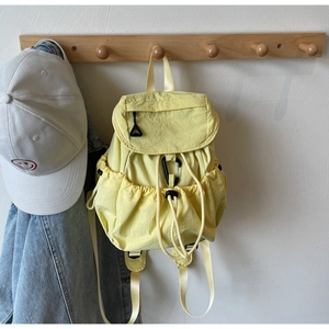 Dettaglio dello zaino in nylon giallo chiaro con coulisse, patta e tasche laterali