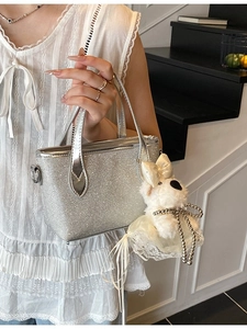Silver glitter crossbody bag with a cute plush dog pendant shown in a fashion setting