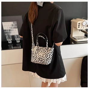 Detail of leopard print crossbody bag with pearl bow pendant worn by a model