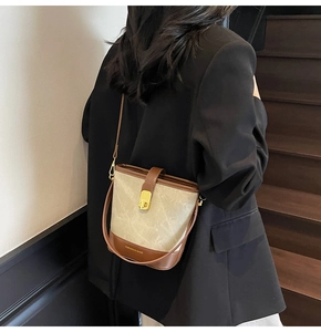 Side view of woman wearing a vintage marble pattern bucket bag with brown leather accents