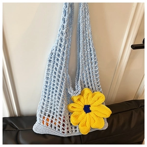 Detail of blue crochet tote bag with large yellow flower and summer beach fruit