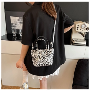 Detail showing leopard print crossbody bag with pearl bow charm and patterned strap