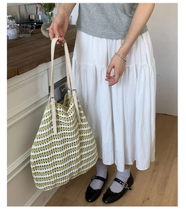 Detail of green and beige striped woven tote bag with adjustable leather handles