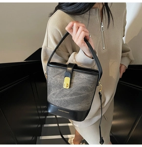 Detail of grey distressed texture bucket bag with gold hardware and logo on model