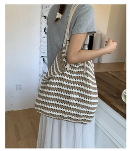 Detail of hand-woven striped straw tote bag featuring adjustable leather shoulder straps