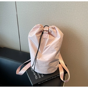 Detailed shot of pink drawstring bag with black D-ring hardware and textured nylon fabric