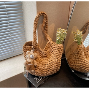 Detail of hand-woven beige cotton tote bag with cute bear charm and small daisies