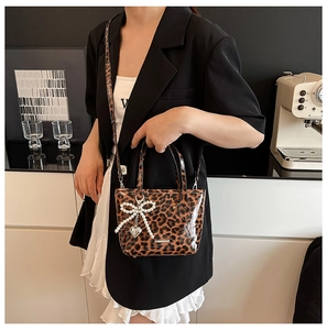 Detail of leopard print bag with glossy finish plus pearl bow and metal heart charm