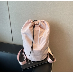 Close-up of pink nylon drawstring bucket bag with black metal handles and cord locks