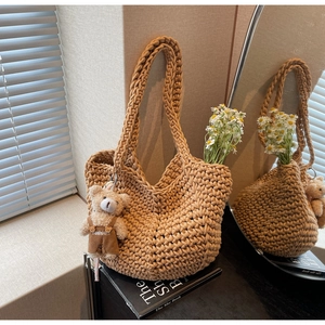 Detail of khaki hand-woven tote bag with cute teddy bear charm and daisy decor