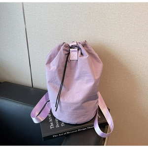 Close-up of light purple drawstring bucket bag with pleated nylon texture on books