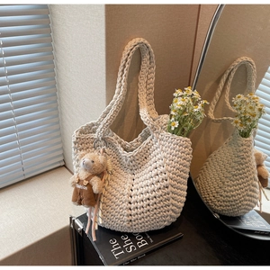 Detail of cream cotton woven shoulder bag with cute teddy bear charm and floral accents