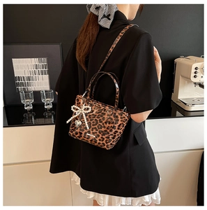 Detailed view of leopard print crossbody bag with pearl bow and metal heart charms