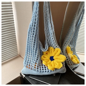 Detail of light blue crochet shoulder bag featuring a large yellow handmade flower