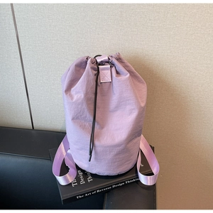 Close-up of lilac drawstring bucket bag with textured nylon fabric and woven strap