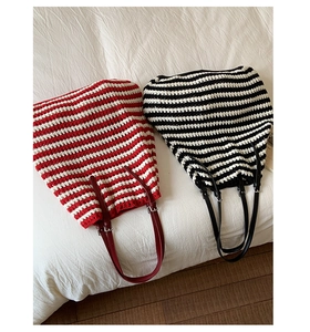 Close-up of woven straw tote bags with red and black stripes and leather straps